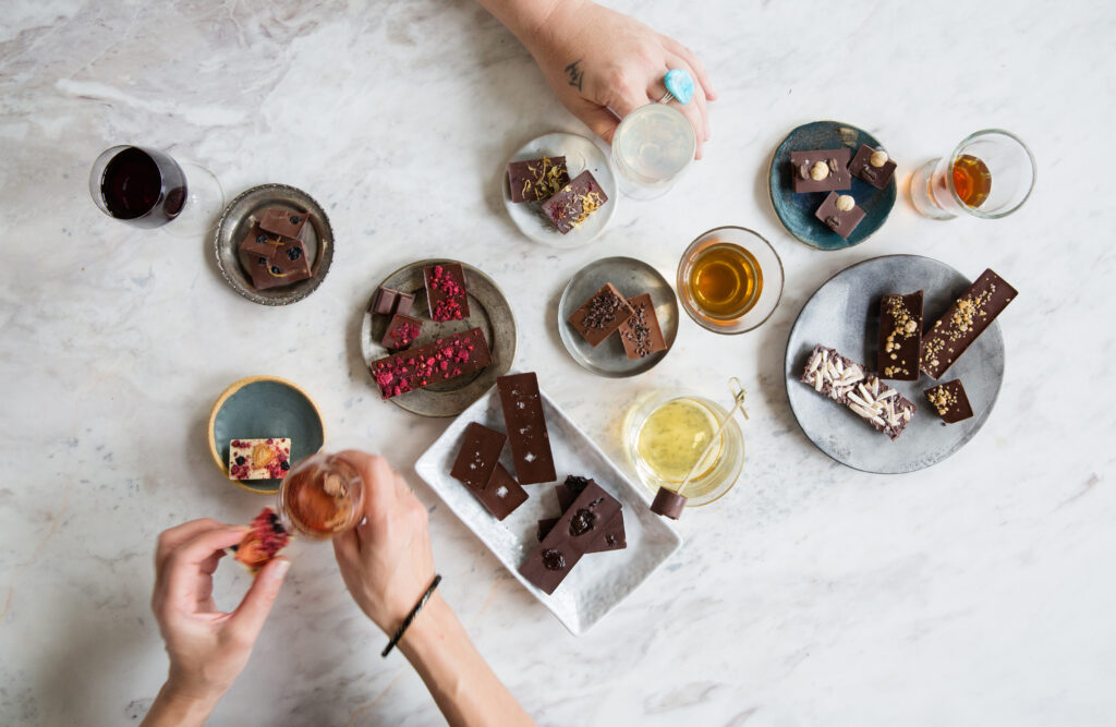 Overhead shot of many small plates with various tavernier chocolate bars and wines to pair